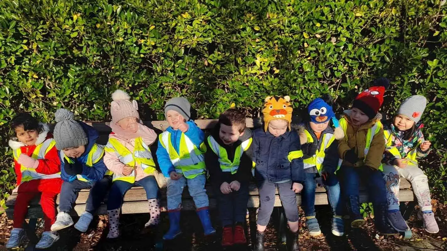 Nursery children sitting together on a bench in the garden at Ready Steady Go Childcare Weston-super-Mare