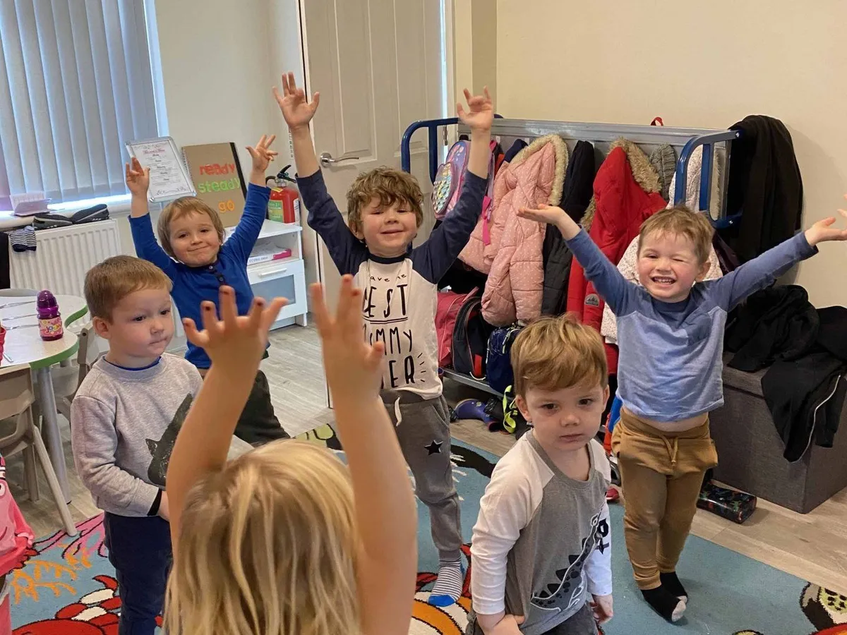 Nursery children cheering with their arms in the air during a group activity at Ready Steady Go Childcare Worle
