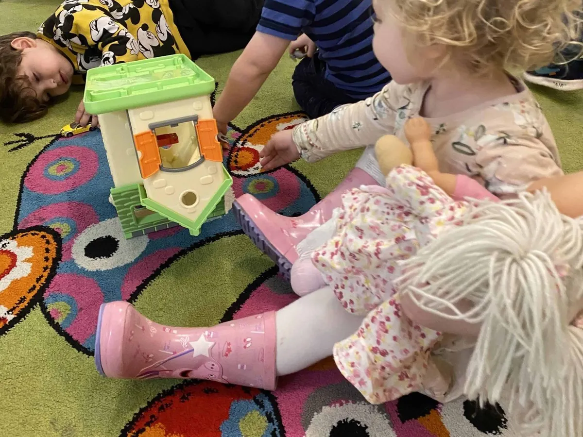 Toddlers playing with small world toys on the rug in the toddler room at Ready Steady Go Childcare Worle